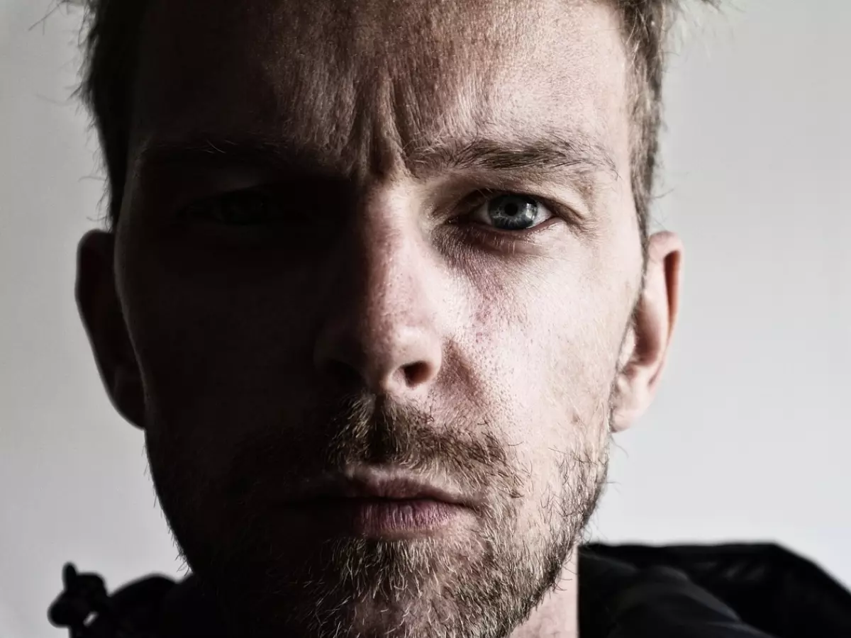 A man sits at a desk looking at a computer monitor. He has a puzzled expression on his face, and his hand is on his chin. The man appears to be considering something.